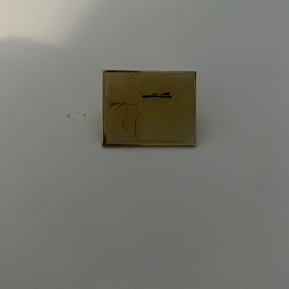 gold pin with snow man on it